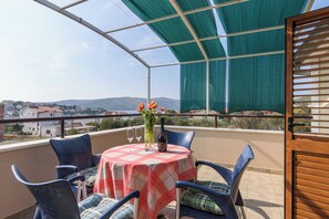 A balcony with a table set for two, chairs, a vase with flowers, and a bottle of wine. - A3 – apartment Robi with shared heated pool & balcony, near the beach (Seget Vranjica)