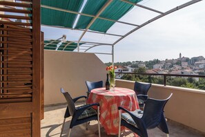 A terrace with a table, chairs, and a view of a town.