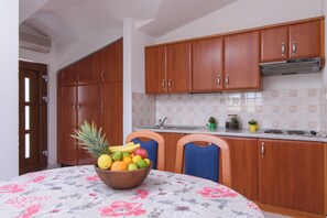A kitchen with wooden cabinets, a fruit bowl on the table, and a tiled backsplash.
