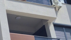 A multi-story building with balconies, air conditioning units, and a window with a shutter. - Sky 47 apartment - modern comfort with free parking (Ohrid)