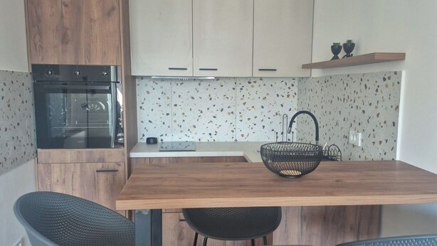 A modern kitchen with a wooden island, bar stools, and pendant lighting. - Sky 47 apartment - modern comfort with free parking (Ohrid)