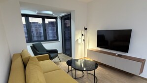 A modern living room with a sofa, a coffee table, a TV, and a floor lamp. - Sky 47 apartment - modern comfort with free parking (Ohrid)