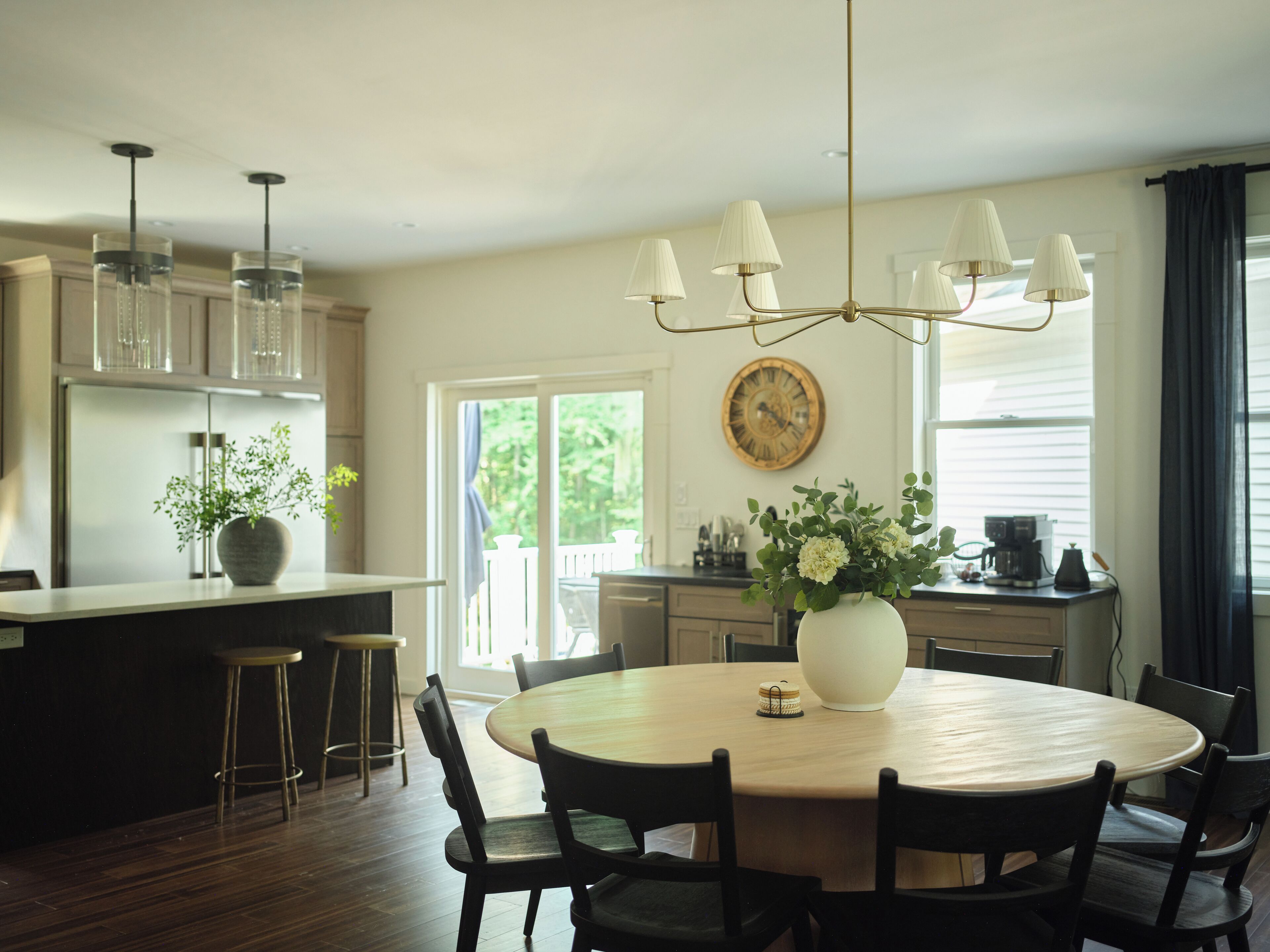 Una cocina moderna con una isla central, iluminación colgante y una mesa redonda con sillas.