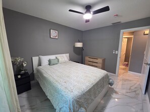 Ein Schlafzimmer mit einem Bett, einem Nachttisch, einer Lampe und einem Deckenventilator.