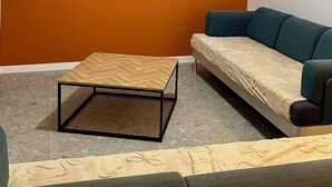 A room with an air conditioning unit, a flat-screen TV mounted on the wall, a wooden coffee table, and a sofa.