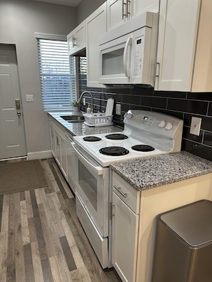 A kitchen with white cabinets, a stainless steel stove, a microwave, and a granite countertop.