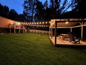 A backyard with a wooden deck, a covered seating area, and string lights. - Brand-new Log Cabin On The Creek, Direct Windrock Trial Access Sleep 8 (Oliver Springs)