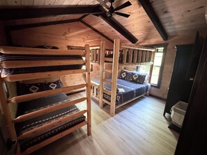 A wooden cabin interior with bunk beds and a ceiling fan.