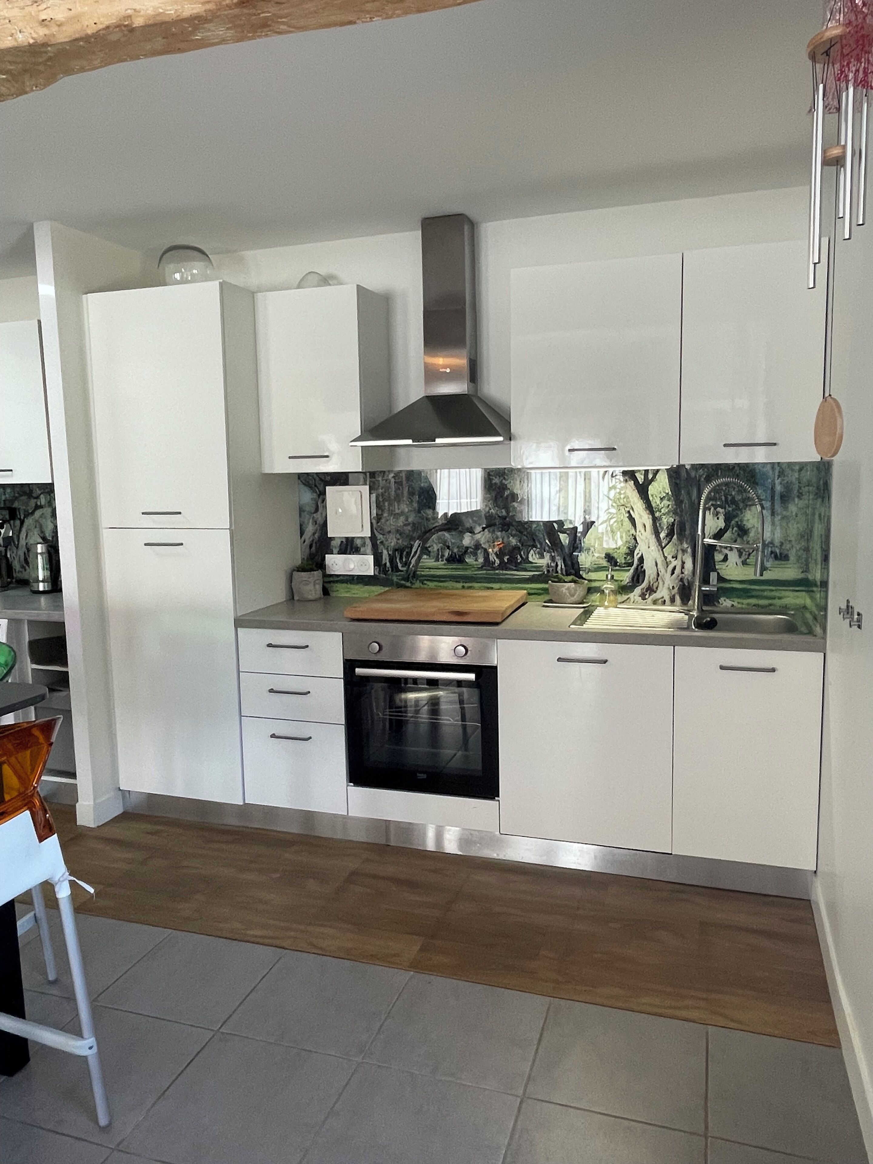 A modern kitchen with white cabinetry, a stainless steel oven, and a decorative backsplash.