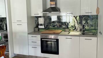 A modern kitchen with white cabinetry, a stainless steel oven, and a decorative backsplash.
