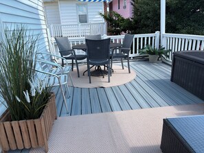 A wooden deck with outdoor furniture, including a table and chairs, surrounded by white railings. - 5 Bedroom Beach House Steps to Beach and Boardwalk (Ocean City)