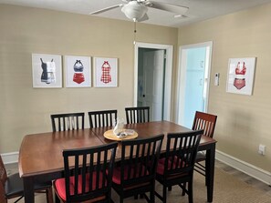 A dining room with a wooden table and six chairs, a ceiling fan, and framed artwork on the walls. - 5 Bedroom Beach House Steps to Beach and Boardwalk (Ocean City)