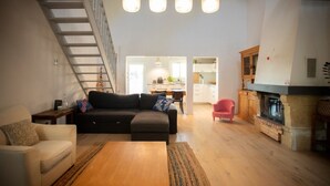 A modern living room with a sofa, a coffee table, and a fireplace. There is a staircase leading to an upper level. - Piano in the Shadow of the Festival (La Roque-d'Anthéron)