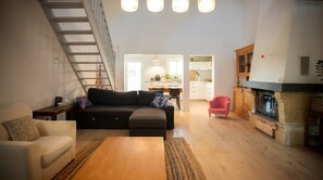 Ein modernes Wohnzimmer mit Sofa, Couchtisch und Kamin. Eine Treppe führt auf eine obere Ebene.
