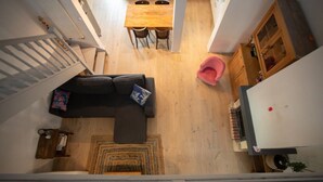 A compact living space with a staircase, a sofa, a dining table, and a small kitchen area. - Piano in the Shadow of the Festival (La Roque-d'Anthéron)