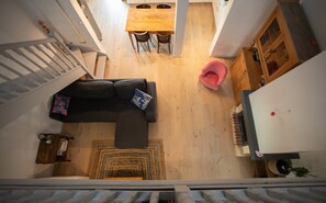 Ein kompakter Wohnbereich mit Treppe, einer Couch, einem Esstisch und einer kleinen Küchenzeile.