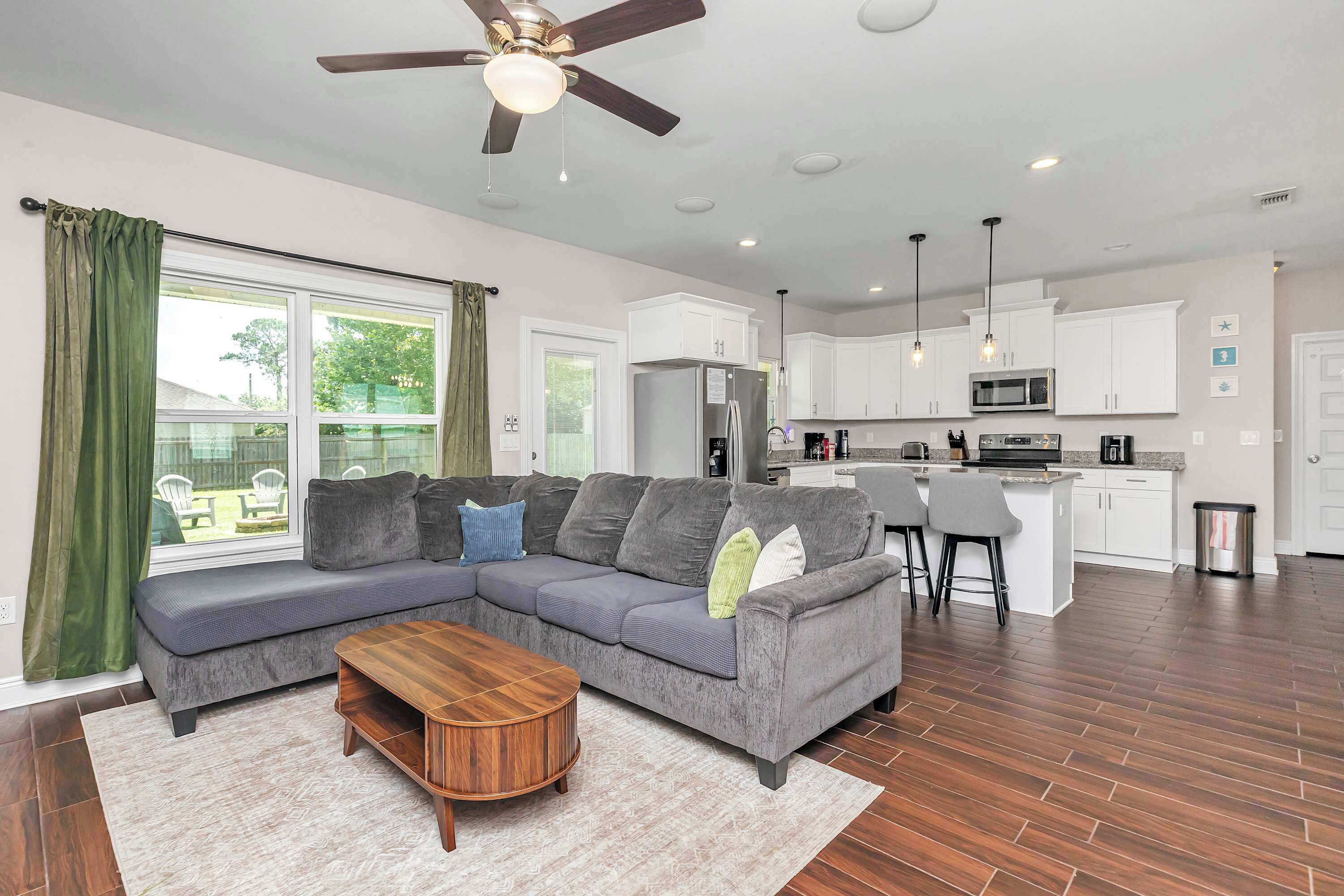 A modern living room with a sectional sofa, a wooden coffee table, and a ceiling fan.