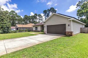 A single-story house with a garage, a front lawn, and a driveway. - Oyster Cove: Pets Allowed, Grill, Pong, Beach! (Navarre)