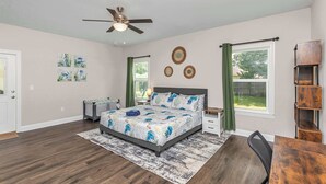A bedroom with a bed, a ceiling fan, a desk, a chair, and a window with curtains. - Oyster Cove: Pets Allowed, Grill, Pong, Beach! (Navarre)
