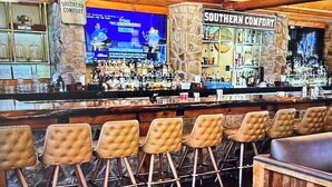 Un espace bar avec un plafond en bois, des tabourets de bar et un écran de télévision.