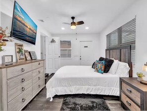 A bedroom with a bed, a dresser, a ceiling fan, and a TV mounted on the wall. - Villa 2 Miles Beach 7 beds Sleeps 12 BBQ 5min Big Easy Casino & Aventura Mall (Hallandale Beach)