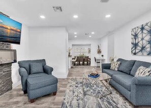 A modern living room with two grey sofas, a coffee table, and a TV mounted on the wall.