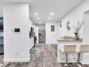 A modern kitchen with a stainless steel refrigerator, white cabinetry, and a marble countertop. - Villa 2 Miles Beach 7 beds Sleeps 12 BBQ 5min Big Easy Casino & Aventura Mall (Hallandale Beach)