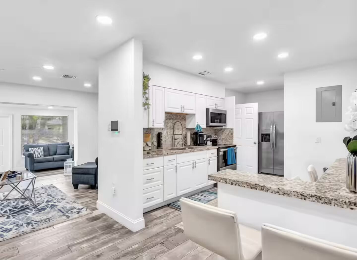 A modern kitchen with white cabinetry, granite countertops, and stainless steel appliances.