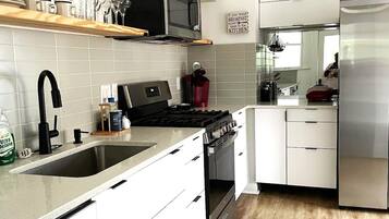 A modern kitchen with white cabinetry, a stainless steel refrigerator, a microwave, and a stove.