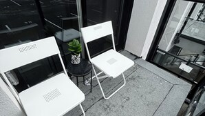 Ein Balkon mit zwei weißen Stühlen und einem kleinen Tisch mit einer Pflanze.