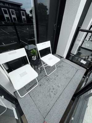 A balcony with two white chairs and a small table with a plant. - 1 Bedroom Condo/6 minutes from Niagara Falls. (Niagara Falls)