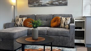 Ein modernes Wohnzimmer mit einem Ecksofa, einem Couchtisch und einem Gemälde an der Wand.
