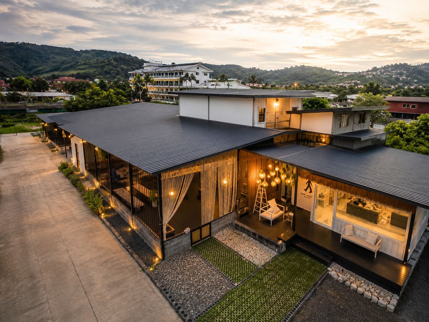 A modern hotel with a flat roof, large windows, and a well-lit outdoor seating area.