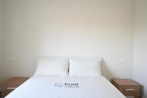 A simple, clean hotel room with a bed, two nightstands, and a logo on the bedspread. - S373 – Sirolo, new one-bedroom apartment with a/c, convenient to the beach (Sirolo)