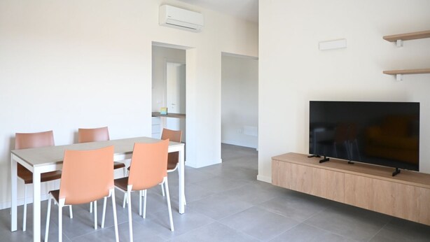 A modern living room with a dining area, a flat-screen TV, and a built-in wooden cabinet. - S373 – Sirolo, new one-bedroom apartment with a/c, convenient to the beach (Sirolo)