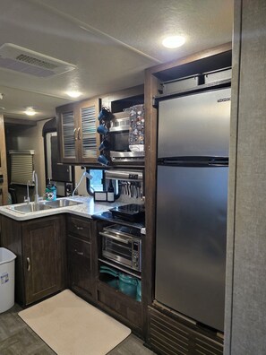 A compact kitchen with a stainless steel refrigerator, a built-in oven, and a microwave. - Jolly RV: 2 bdrm RV in lovely Spring Branch/Canyon Lake/Hill Country w/AC, grill (Spring Branch)