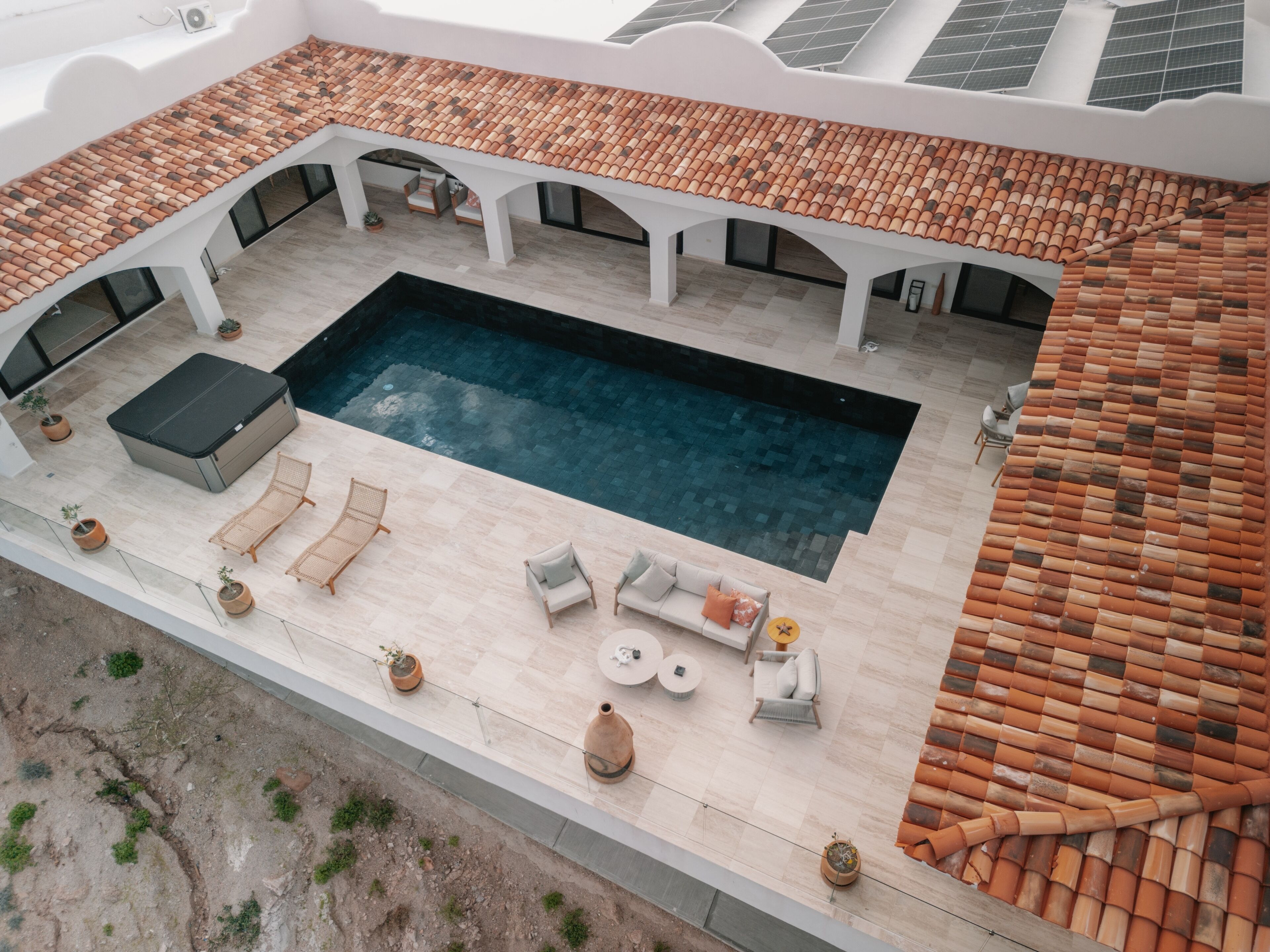Vista aérea de una piscina en la azotea con techo de azulejos, sillas de descanso y un área de estar.