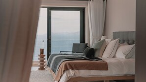 A bedroom with a bed, a bedside table, a lamp, and a view of the sea through a window. - Self Contained Sanctuary & Speedboat (La Paz)