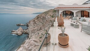 A coastal property with a terrace overlooking the sea, featuring outdoor furniture and potted plants. - Self Contained Sanctuary & Speedboat (La Paz)