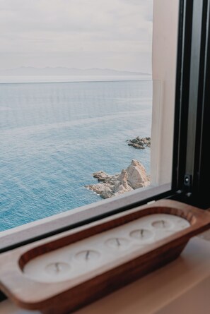 A view of a calm sea with rocky outcrops, a window with a wooden tray, and a white wall. - Self Contained Sanctuary & Speedboat (La Paz)