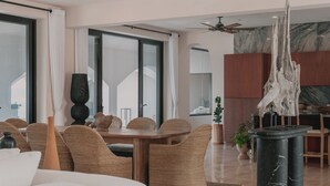 A modern living room with a dining area, large windows, and a ceiling fan. - Self Contained Sanctuary & Speedboat (La Paz)