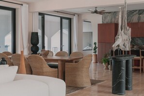 Una sala de estar moderna con comedor, ventanas grandes y ventilador de techo.