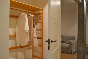 Una habitación con un armario de madera, un sofá gris y una puerta con picaporte negro.