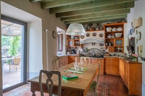 A rustic kitchen with wooden cabinets, a dining table with chairs, and a large window. - Country Charm in Florence (Montebeni)