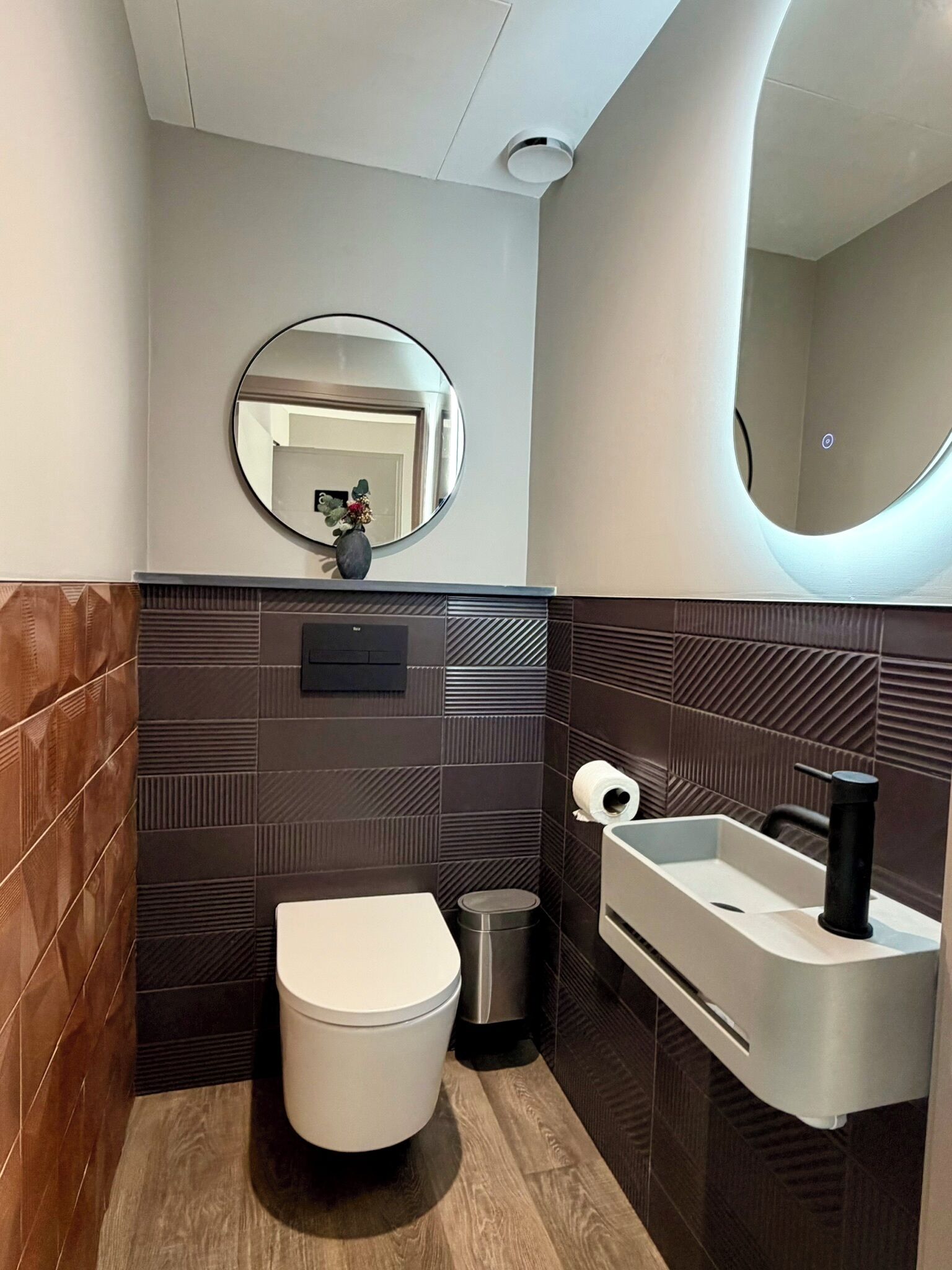 A modern bathroom with a toilet, sink, and mirror.