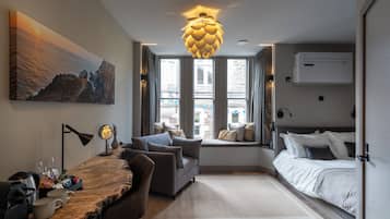 Un dormitorio moderno con cama, sofá, escritorio con lámpara y un amplio ventanal.