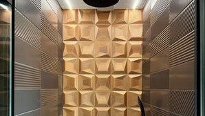 A modern shower with geometric patterned tiles, a black handheld showerhead, and a handheld shower hose. - Uno by the Sea (St Ives)