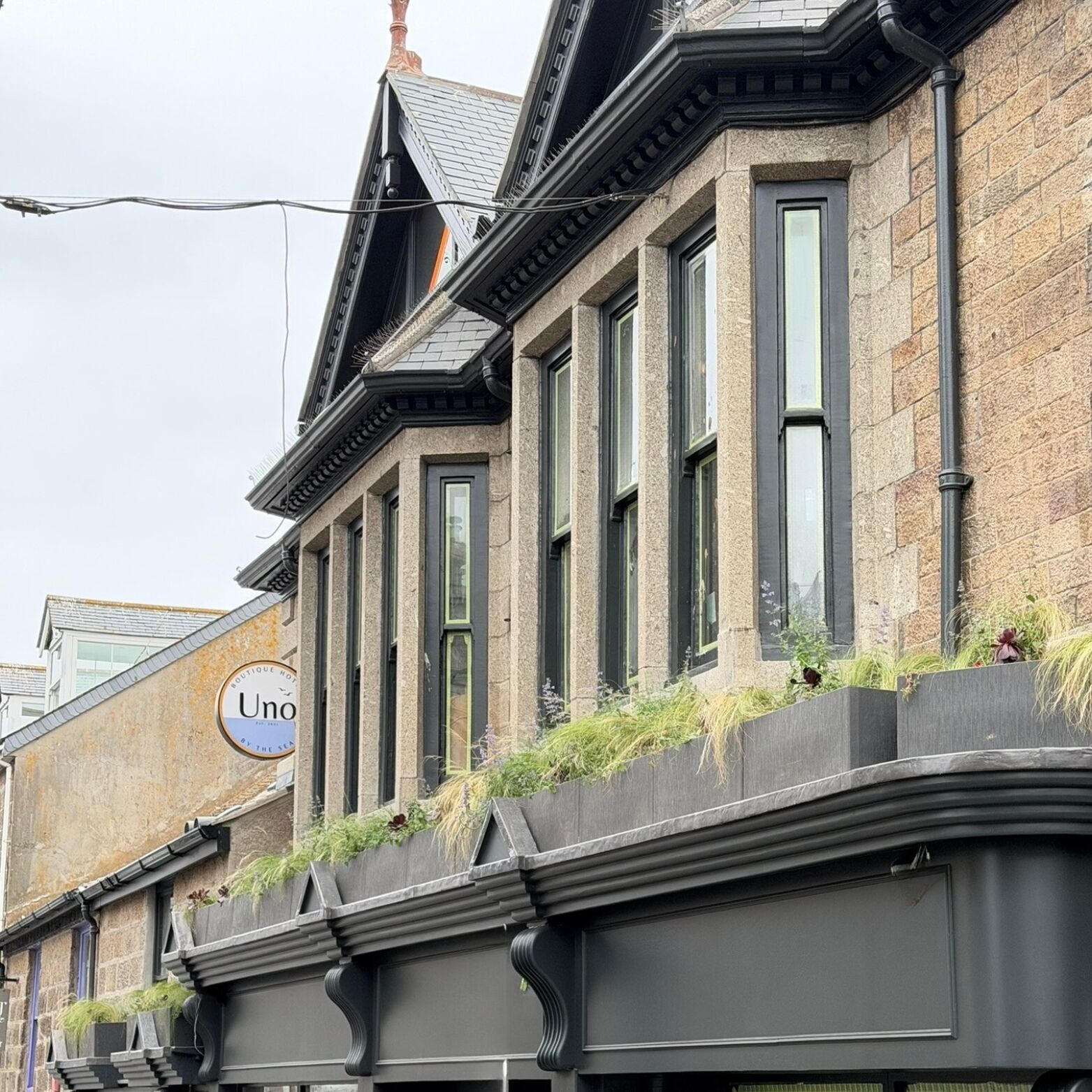 A corner building with a stone facade, multiple windows, and a sign for 'Uno'.