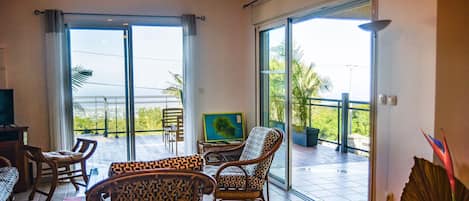 Habitación amplia con balcón, amoblada con sillas y una mesa, y ventanas grandes que ofrecen vistas al exterior.