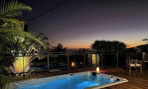 A hot tub on a wooden deck with a view of the sunset.